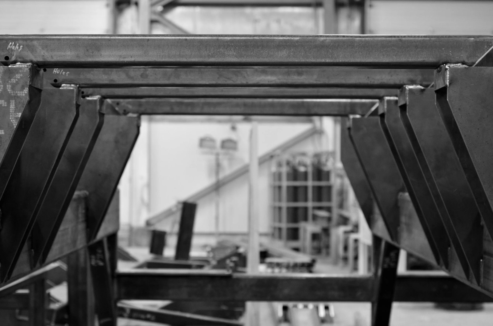 A welded steel frame squared on the bench, with hole positions marked out before drilling